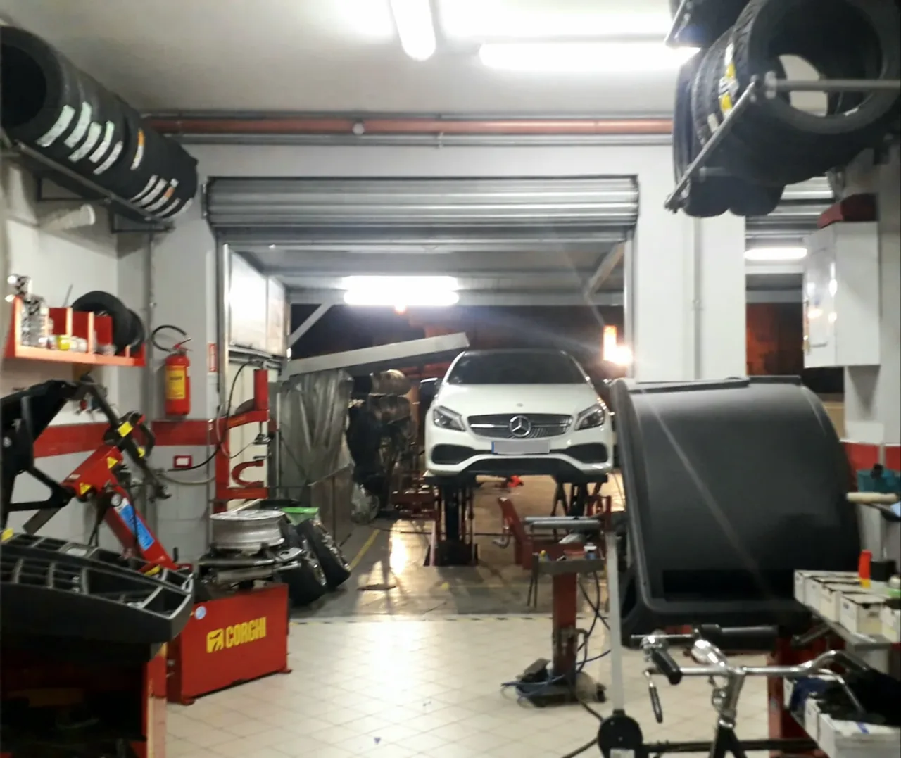 Vista dell’officina e del ponte di lavoro, con la vettura sollevata per l’intervento.